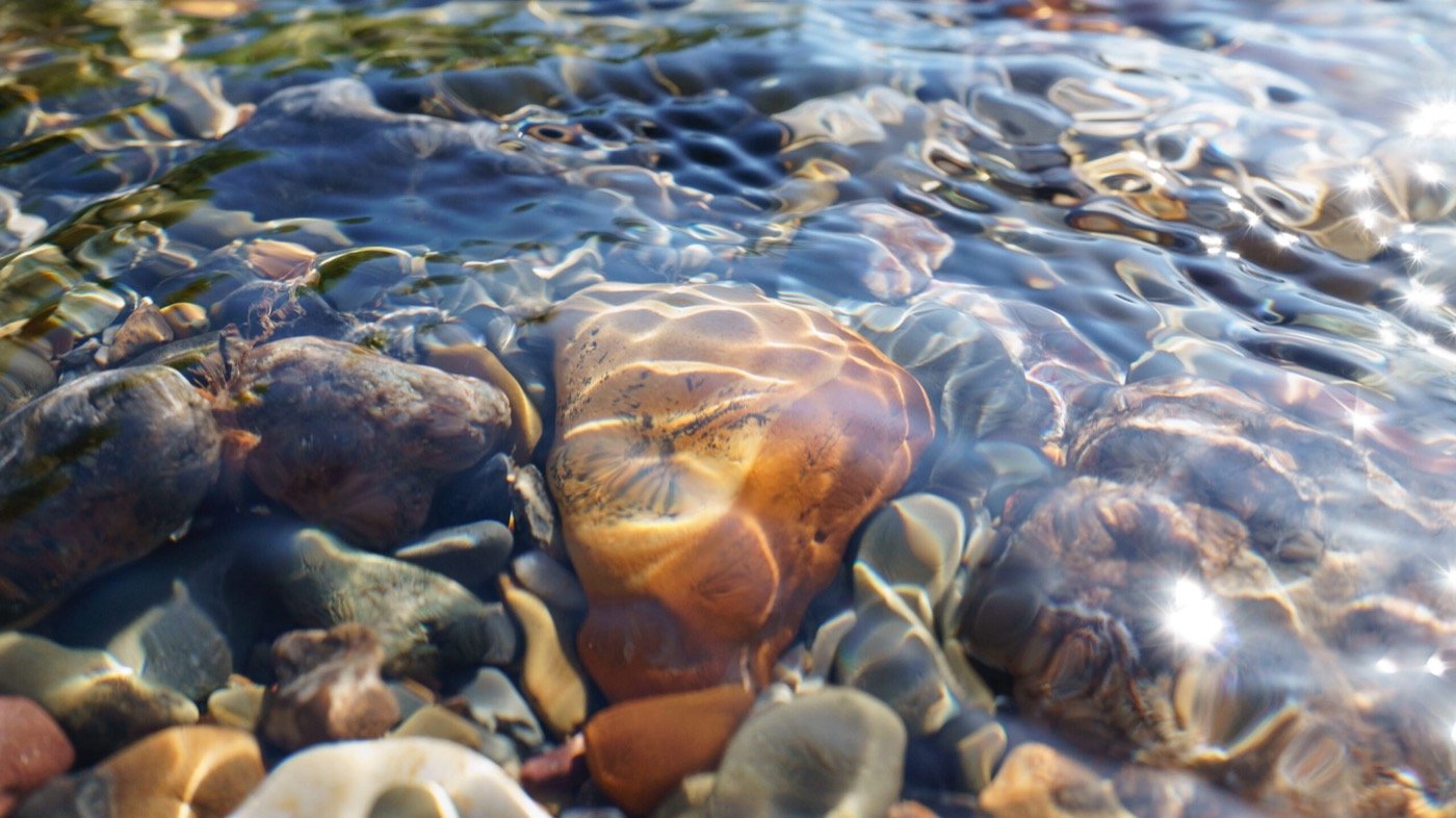 Klares Wasser über runden Kieselsteinen – Ruhe und Klarheit